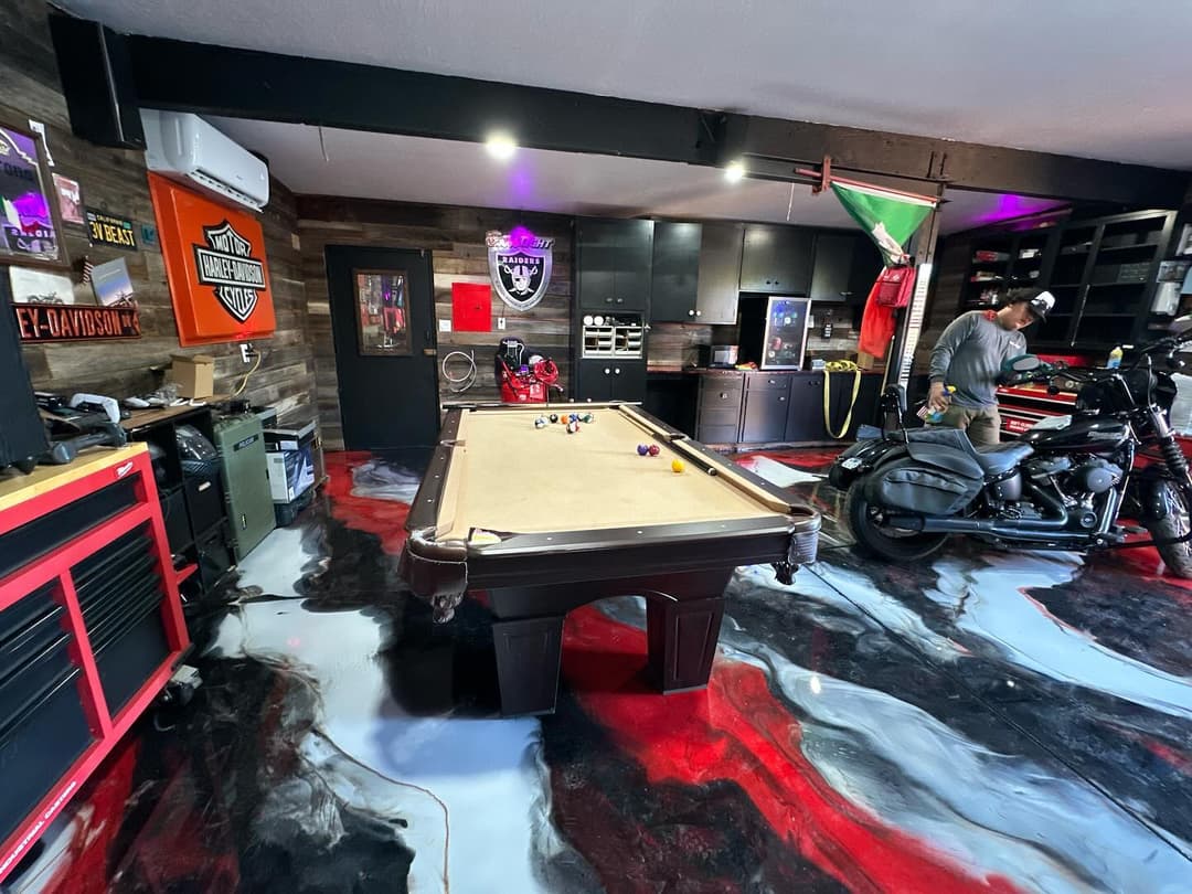 Stylish garage with a pool table, motorcycle, and modern decor featuring red and black epoxy flooring.