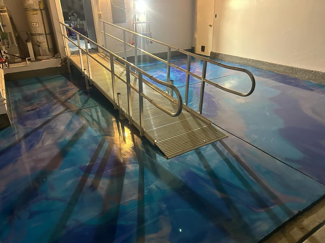 ADA compliant ramp over a blue marbled floor, illuminated for visibility in an indoor setting.