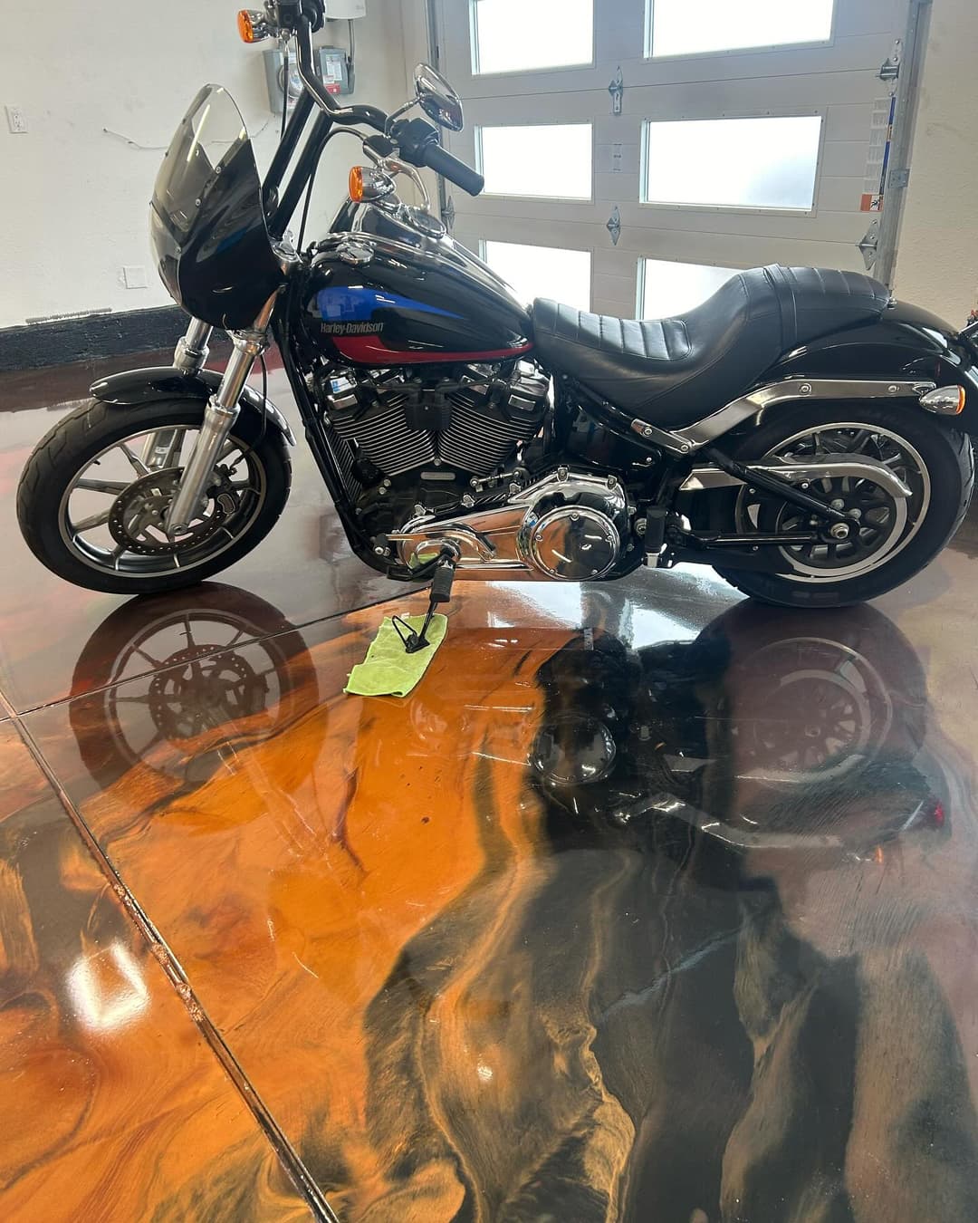 Black Harley-Davidson motorcycle parked on a glossy, multicolored epoxy floor.