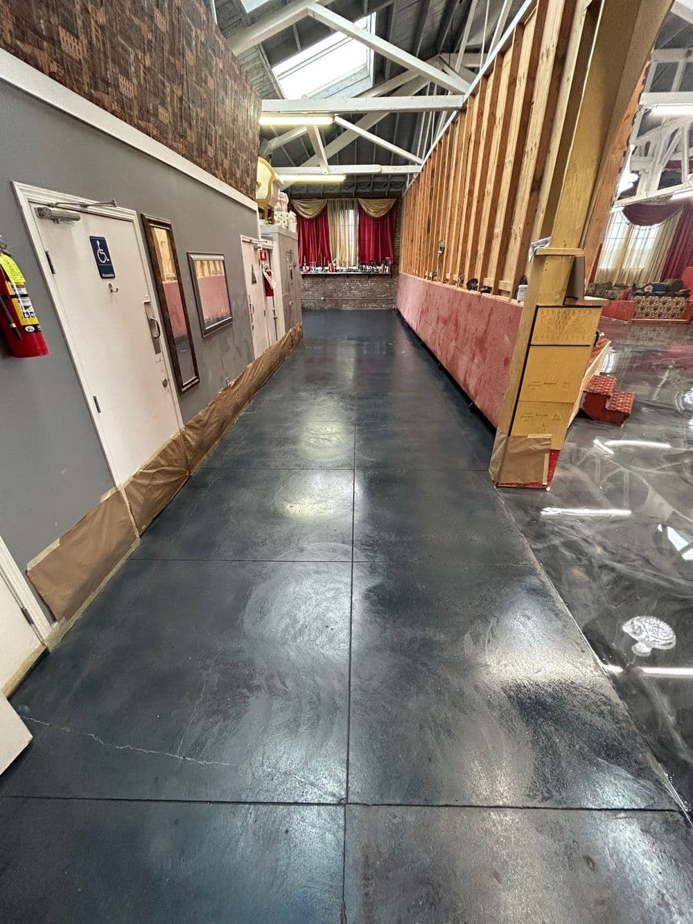 Interior view of a commercial space featuring polished black concrete flooring and renovation elements.