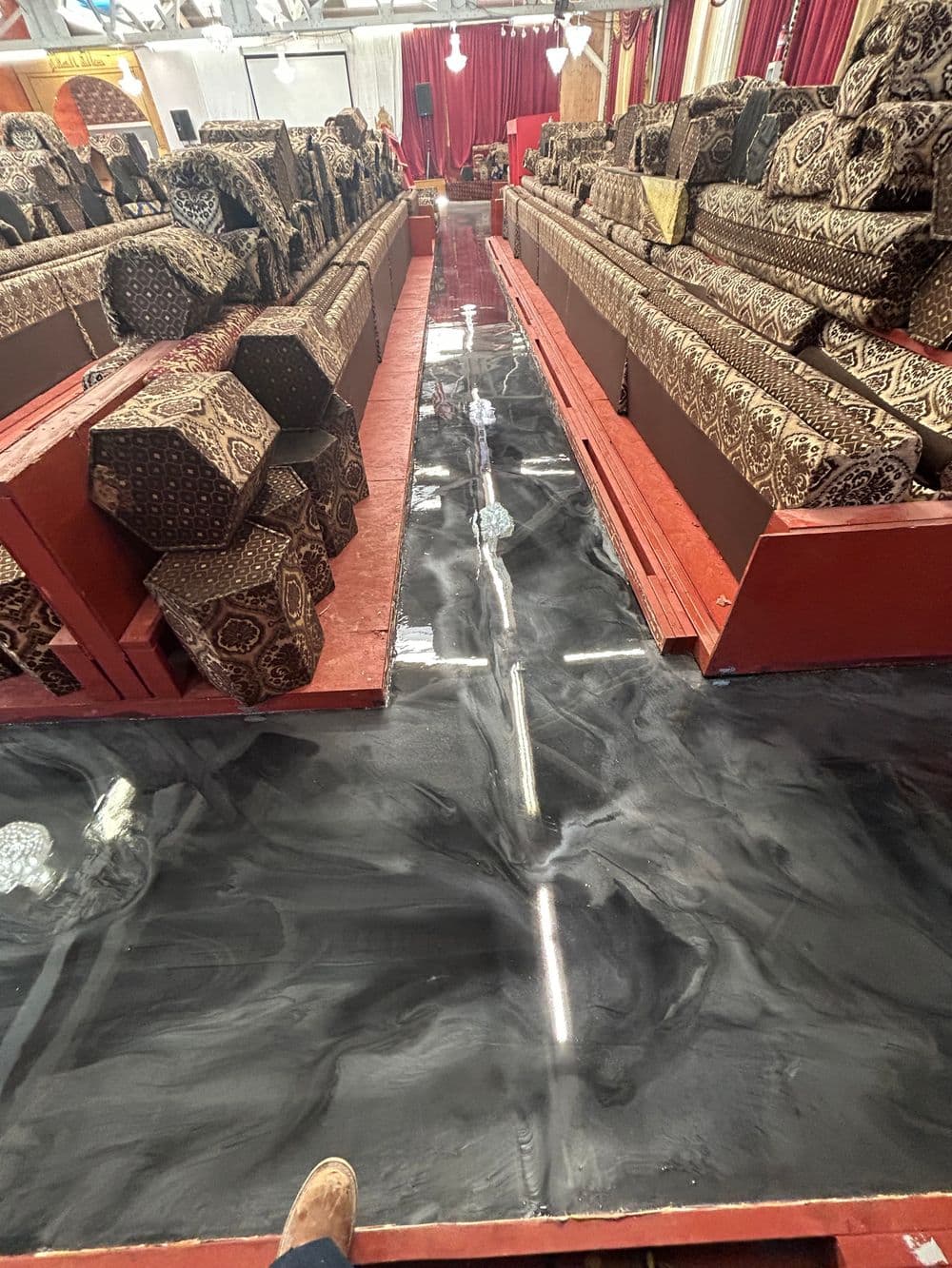 Elegant patterned carpets displayed in a vibrant market with a sleek dark floor.