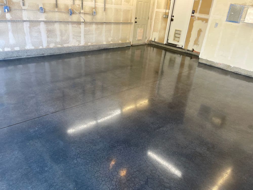 Shiny polished concrete garage floor with walls under renovation and door leading outside.
