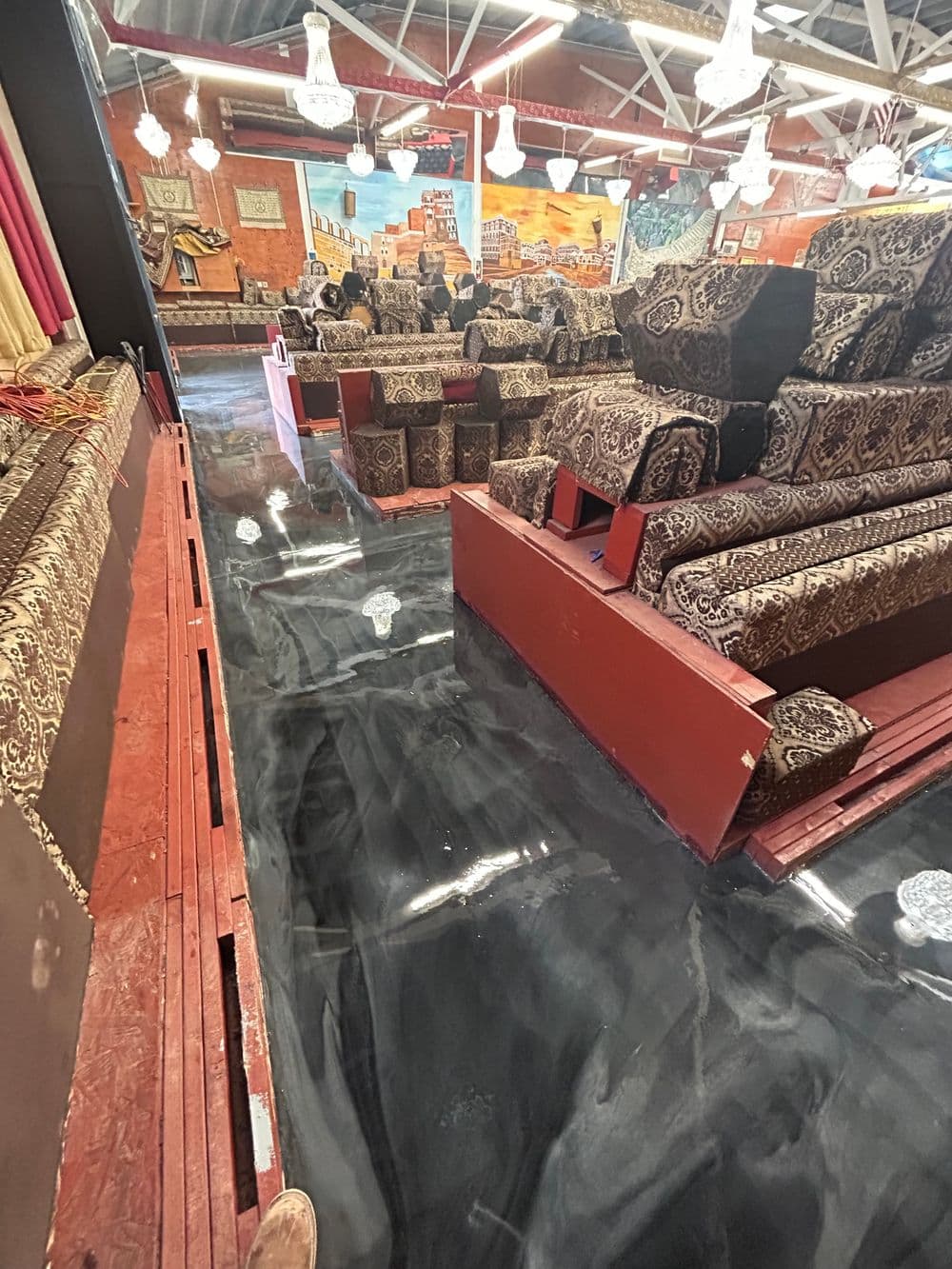 Flooded seating area with patterned upholstery and dark reflective floor in a commercial space.