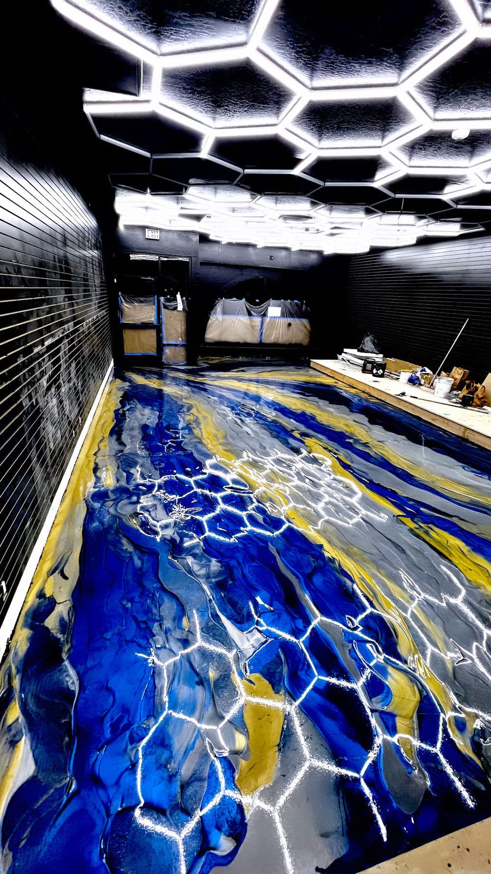 Stunning blue and yellow epoxy floor design in a modern, illuminated interior space.
