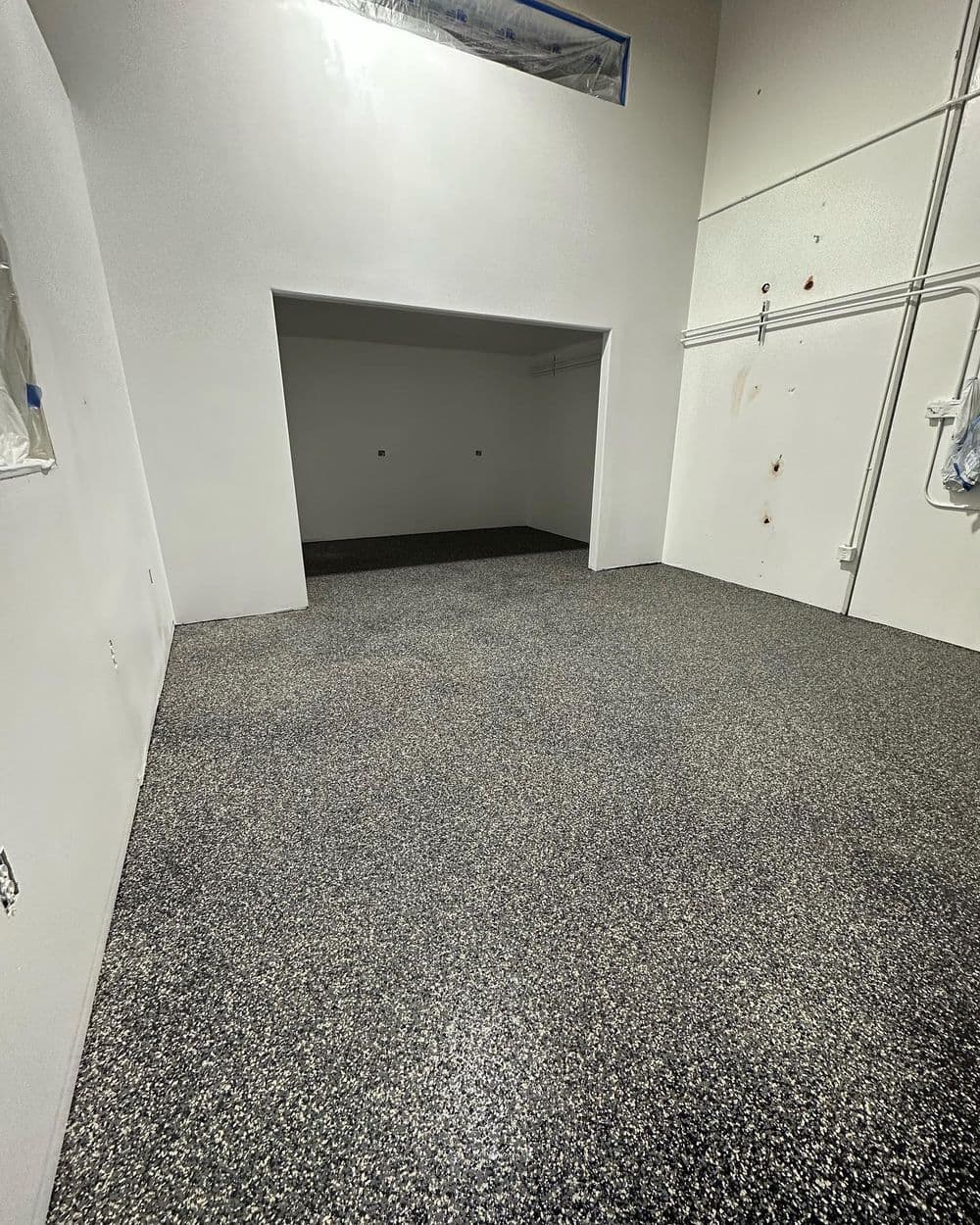 Newly coated epoxy garage floor with a sleek gray and black flake finish. Clean, modern space.