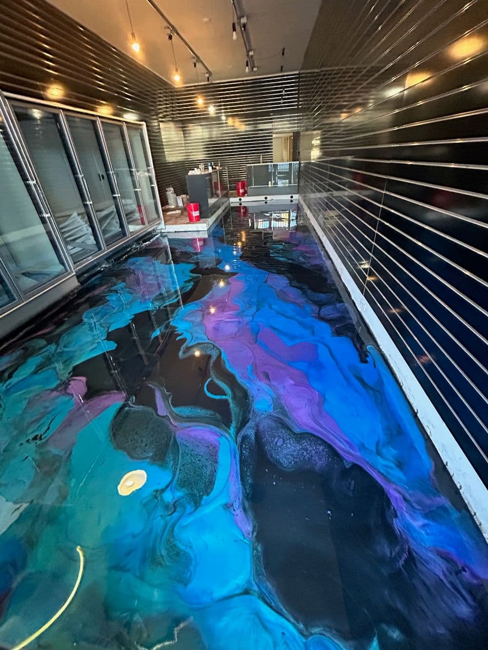 Colorful epoxy resin floor with blue and purple swirls in a modern interior space.